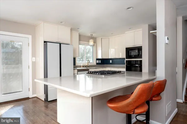 a kitchen with stainless steel appliances granite countertop a refrigerator a stove and a sink with wooden floor