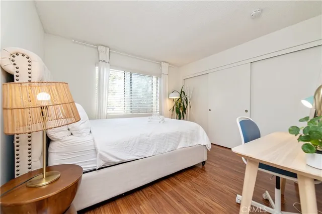 a bedroom with a bed and dresser with wooden floor