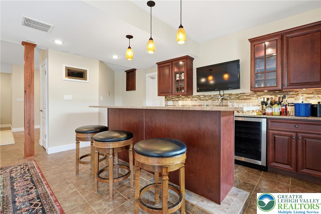 245 East Dell Road Bath, PA 18014 - Photo 65 of 99 A well-appointed entertainment area features a spacious bar with warm cabinetry and inviting tile flooring.