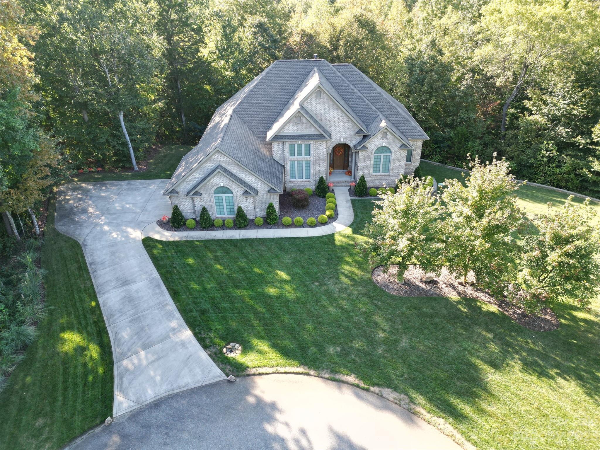 a view of a house with a big yard plants and large trees