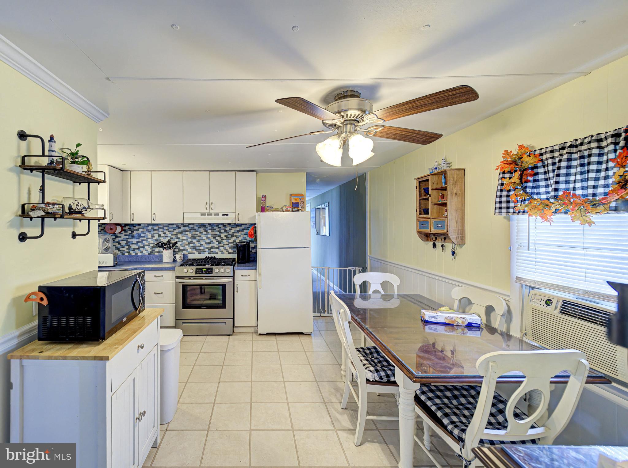 59 Bayshore Mobile Manor Hazlet, NJ 07730 - Photo 11 of 22 a kitchen with a stove a sink a dining table and chairs