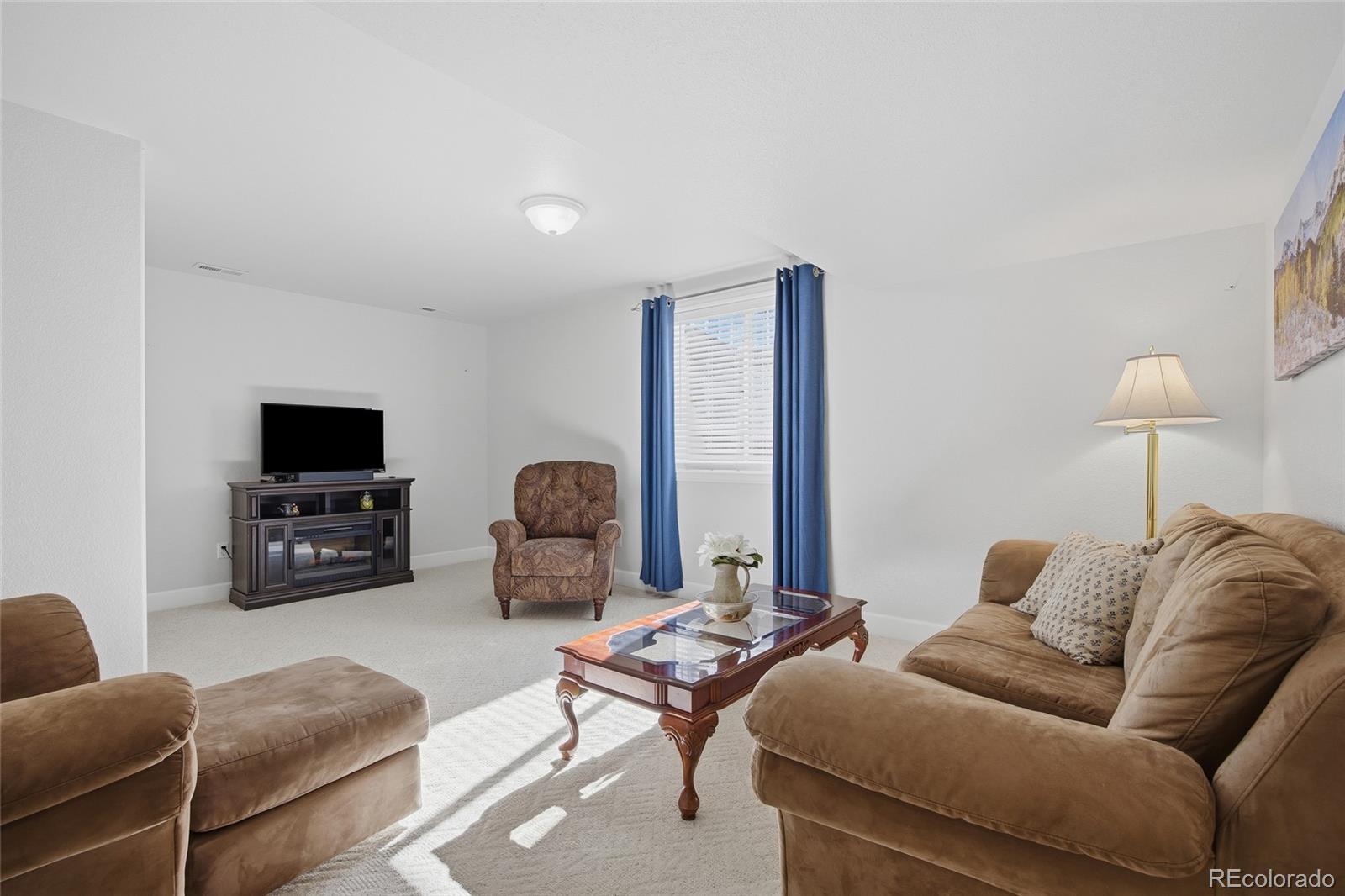 1229 Founders Circle Windsor, CO 80550 - Photo 27 of 45 a living room with furniture a flat screen tv and a fireplace