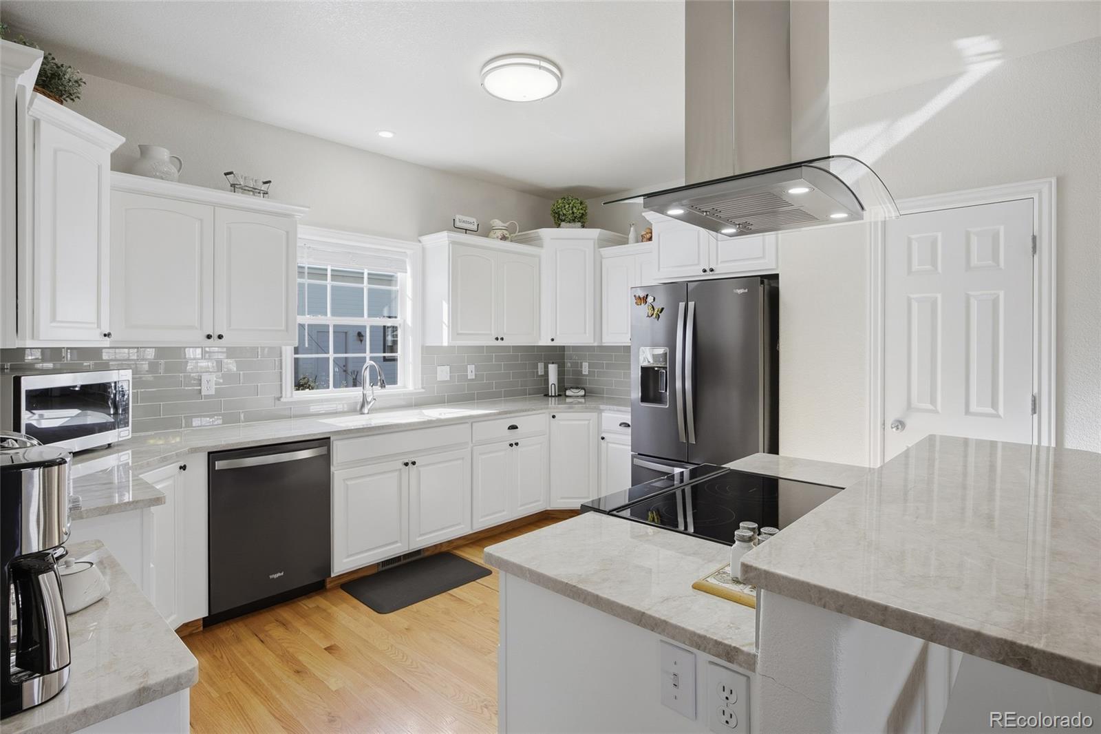 1229 Founders Circle Windsor, CO 80550 - Photo 6 of 45 a kitchen with a sink a stove a refrigerator and white cabinets
