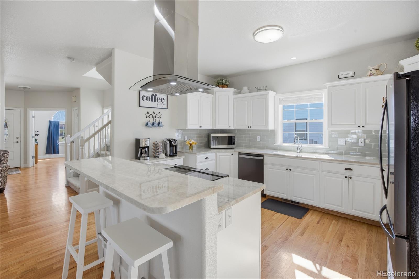 1229 Founders Circle Windsor, CO 80550 - Photo 9 of 45 a kitchen with a sink a stove a refrigerator and white cabinets