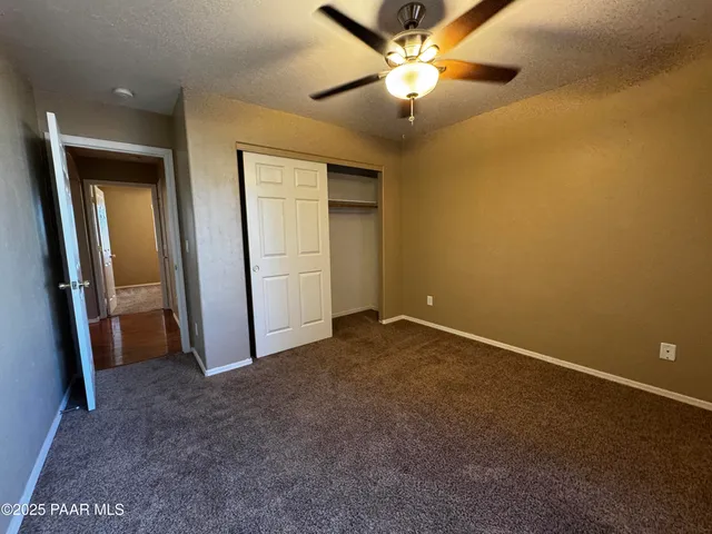 an empty room with closet and a chandelier fan