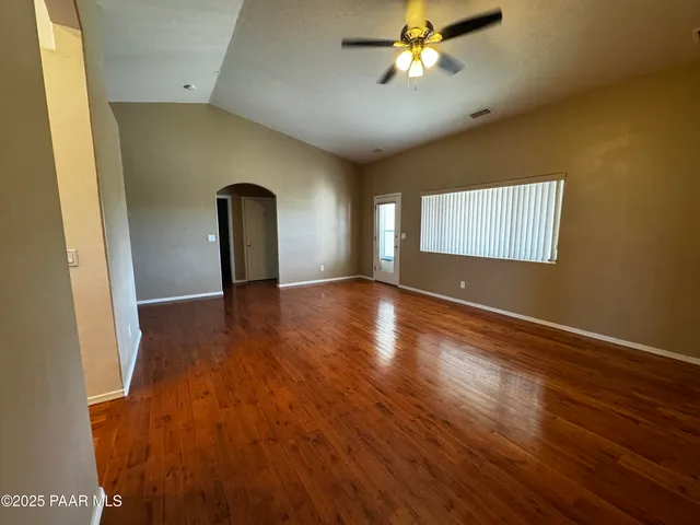 a view of an empty room with window and wooden floor