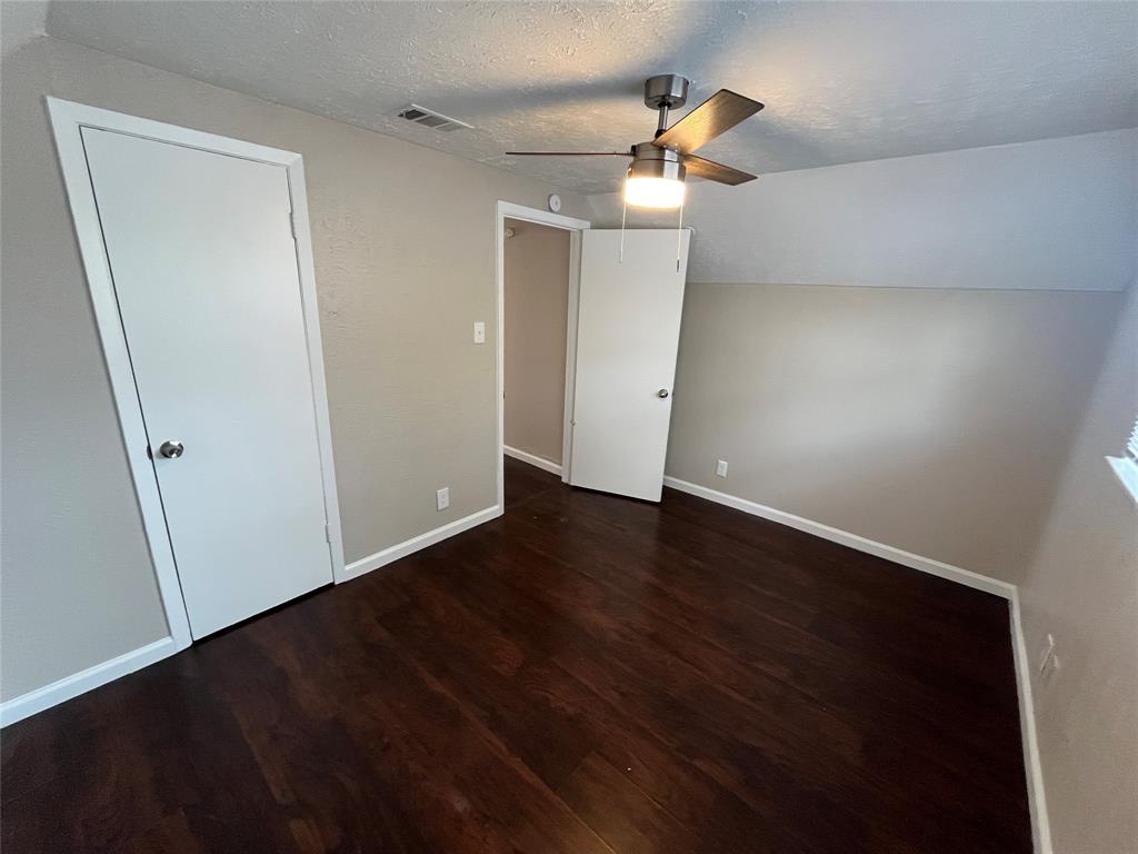 14207 Cimarron Drive Balch Springs, TX 75180 - Photo 15 of 23 Unfurnished bedroom with a textured ceiling, dark wood-style floors, ceiling fan, and vaulted ceiling