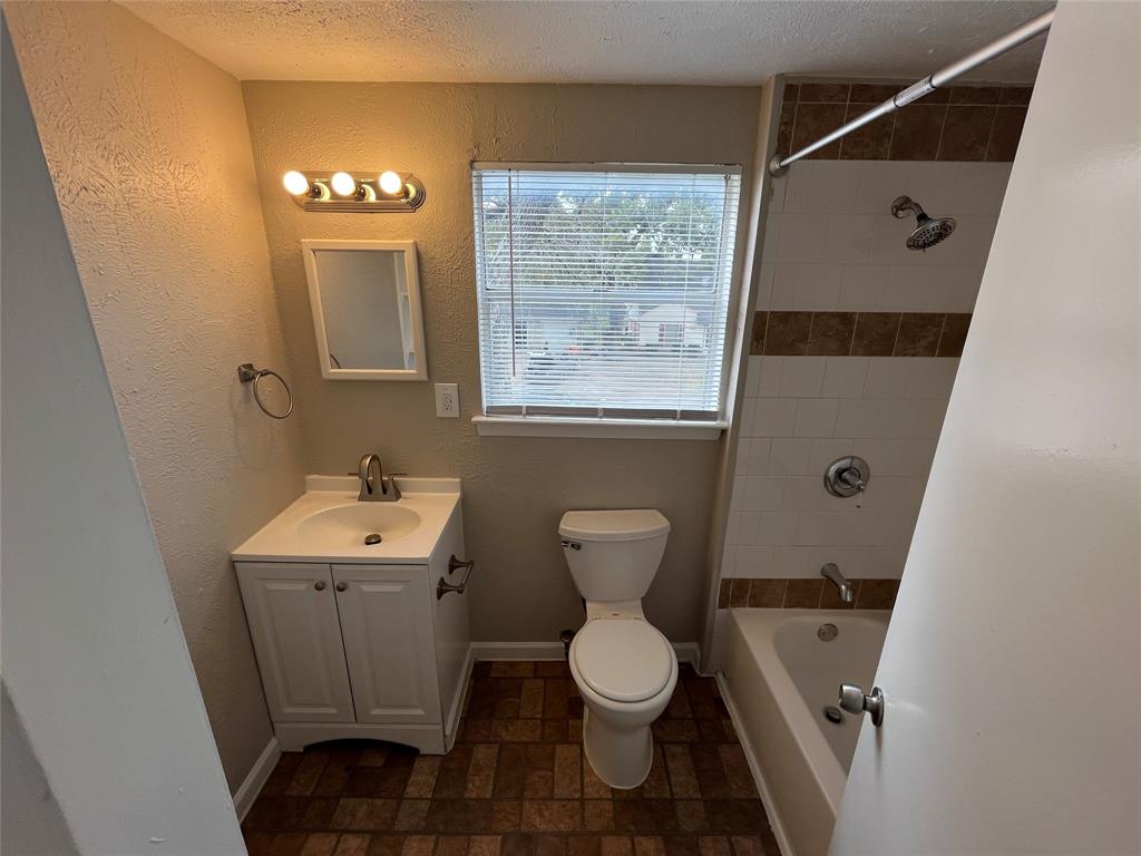 14207 Cimarron Drive Balch Springs, TX 75180 - Photo 18 of 23 Full bath featuring vanity, washtub / shower combination, a textured wall, and a textured ceiling