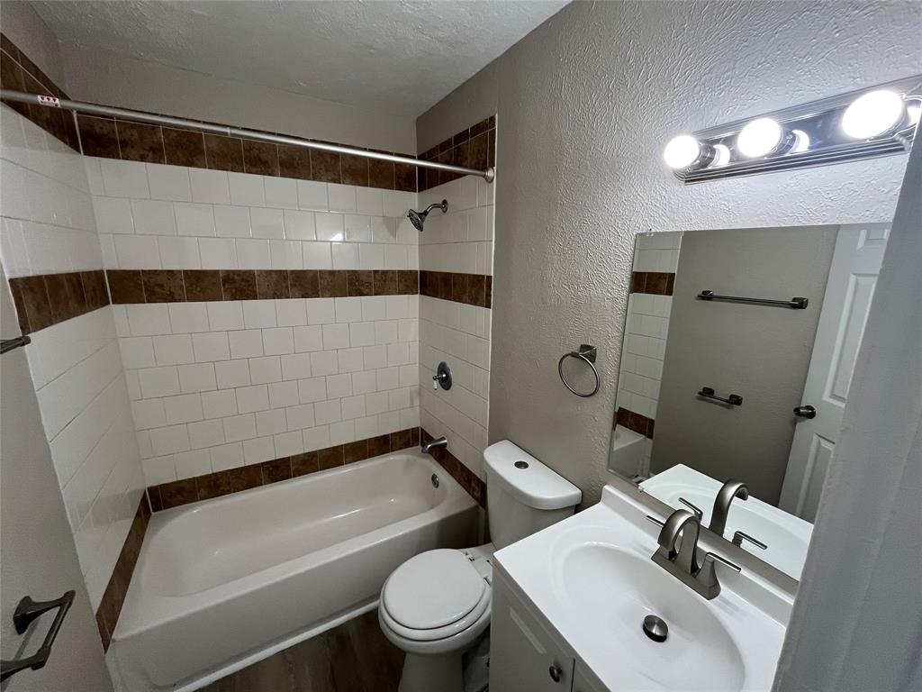 14207 Cimarron Drive Balch Springs, TX 75180 - Photo 7 of 23 Bathroom featuring a textured wall, shower combination, vanity, a textured ceiling, and wood finished floors