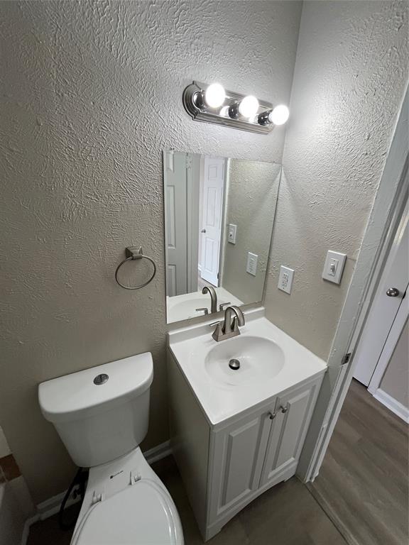14207 Cimarron Drive Balch Springs, TX 75180 - Photo 8 of 23 Half bath with a textured wall, vanity, and dark wood-style flooring