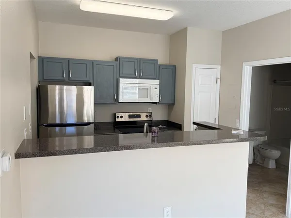 a kitchen with stainless steel appliances granite countertop a refrigerator a stove a sink a counter space and cabinets