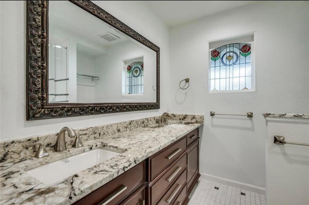 13038 Copenhill Road Dallas, TX 75240 - Photo 10 of 15 Dual undermount sinks, stone-finish countertop, dark wood-finish cabinetry, decorative stained-glass window, and white square tile flooring