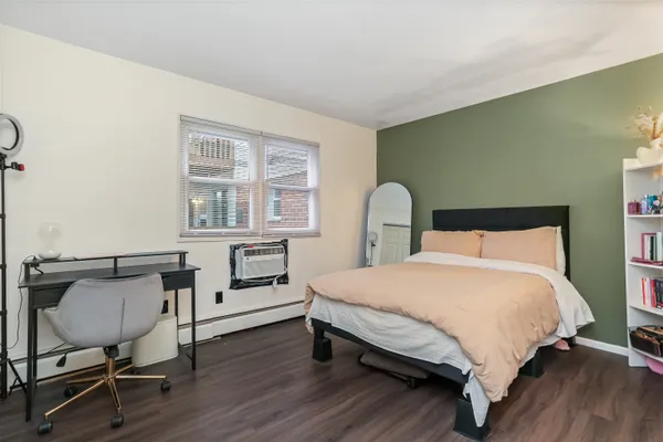 a bedroom with a bed chair and wooden floor