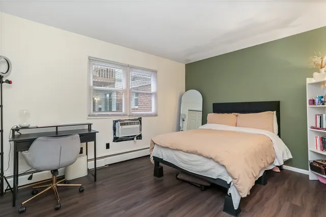 a bedroom with a bed chair and wooden floor