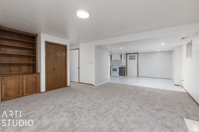 2807 North Ogden Canyon Road Eden, UT 84310 - Photo 39 of 72 Spacious living area featuring light gray carpeting, an integrated wood-finish bookcase with lower cabinetry, and a wood-finish door