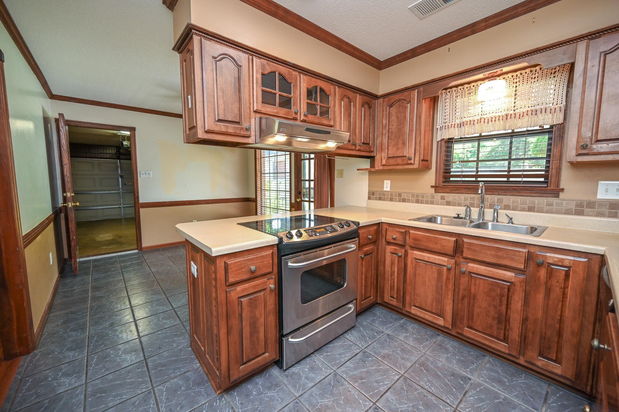 3746 Broadway Road Bartlett, TN 38135 - Photo 10 of 39 Kitchen featuring dark wood cabinetry, light countertops, a stainless steel range, and a dual basin sink.