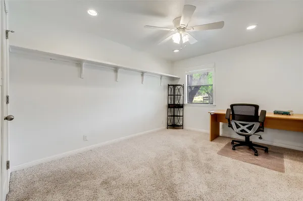 a view of a workspace with furniture and a ceiling fan