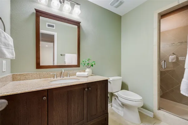 a bathroom with a toilet a sink a vanity a mirror and shower