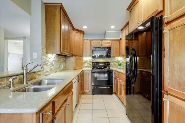 a kitchen with kitchen island granite countertop a sink refrigerator and cabinets
