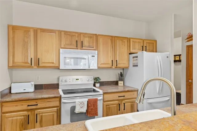 a kitchen with stainless steel appliances granite countertop a stove a sink dishwasher and refrigerator with wooden cabinets