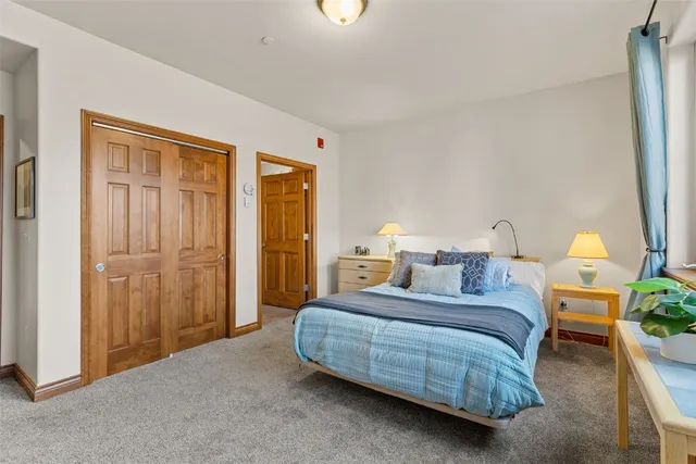a bedroom with a bed a lamp on dresser and a chandelier