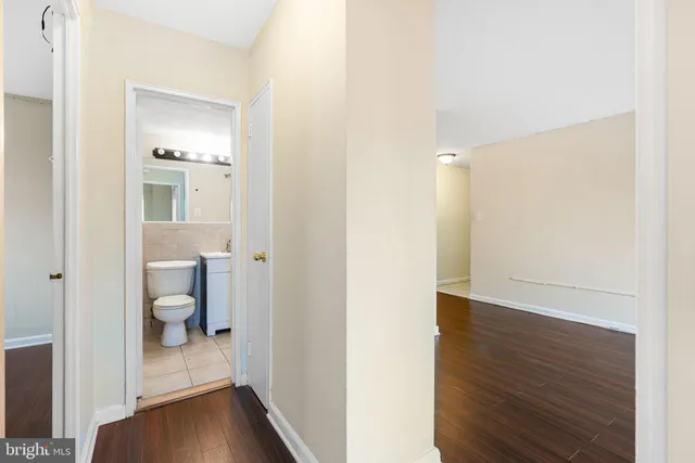 a view of a hallway with wooden floor and a bathroom