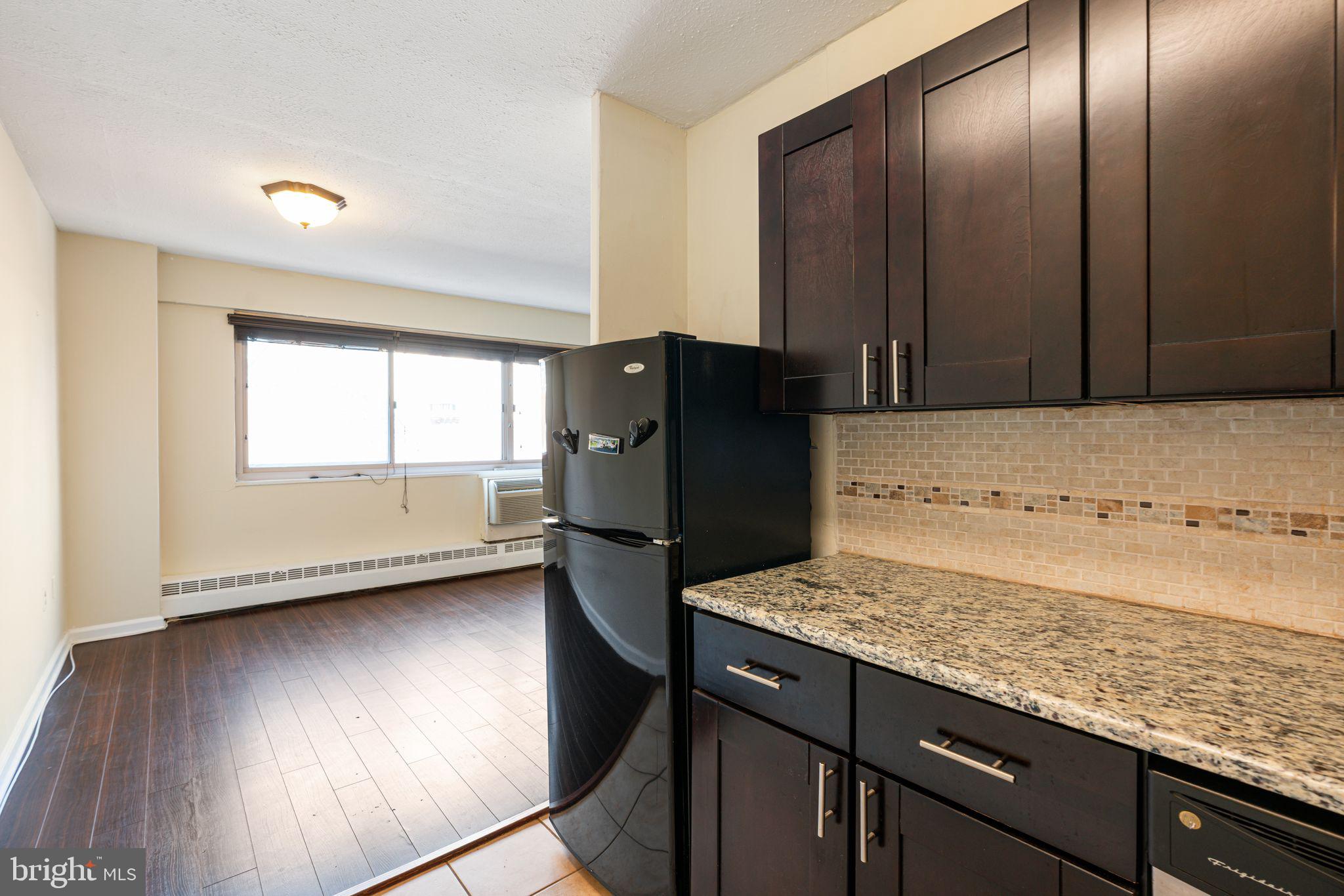 2101 Chestnut Street, Unit 518 Philadelphia, PA 19103 - Photo 7 of 14 a kitchen with granite countertop wooden cabinets and a refrigerator