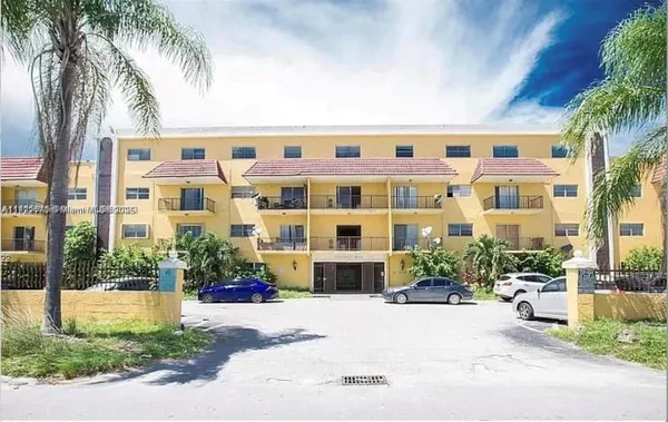 a front view of multi story residential apartment building with yard and sign board
