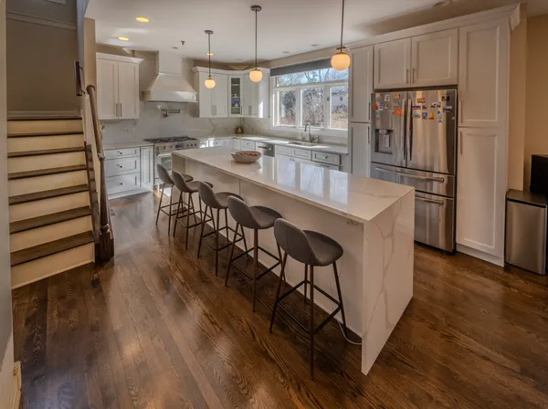 a kitchen with stainless steel appliances granite countertop a refrigerator a stove a sink dishwasher and a dining table with wooden floor