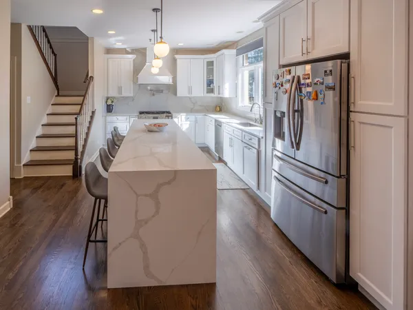 a kitchen with kitchen island white cabinets and stainless steel appliances
