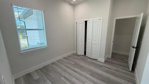 a view of a hallway with wooden floor and a bathroom