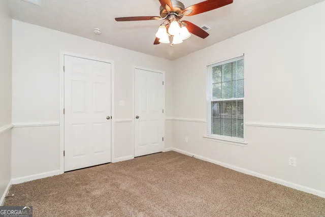 an empty room with windows and fan