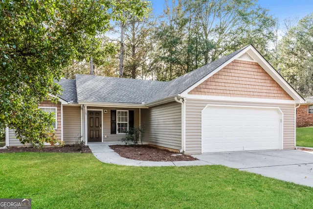 a view of a house with a yard plants and large tree