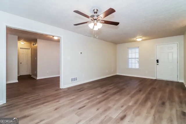 an empty room with wooden floor and windows