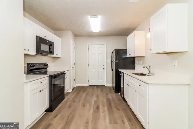 a kitchen with granite countertop a sink stove and refrigerator