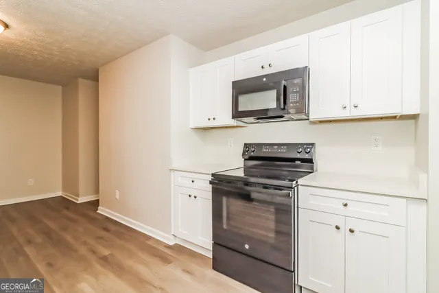 a kitchen with stainless steel appliances granite countertop white cabinets and a stove top oven