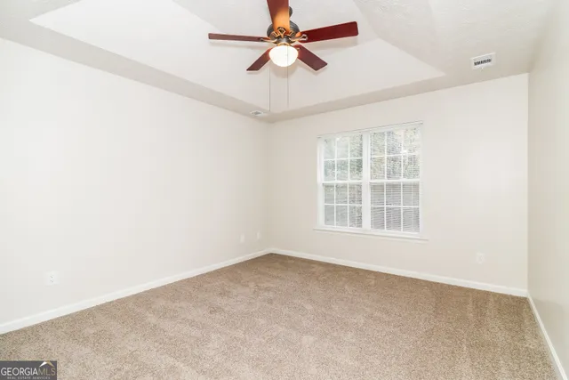 an empty room with a window and a fan