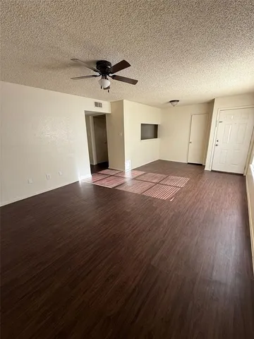 an empty room with wooden floor ceiling fan and windows