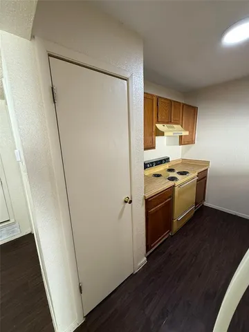 a kitchen with a stove a refrigerator and a wooden floor