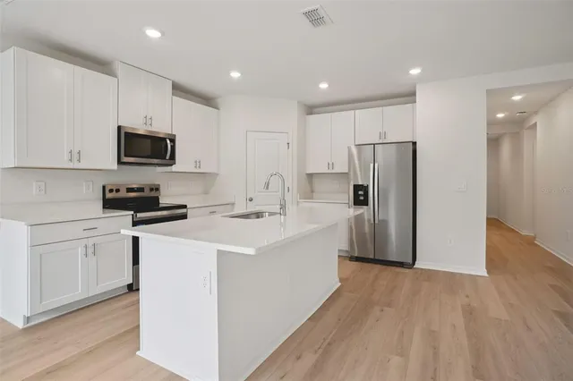 a kitchen with refrigerator a microwave and white cabinets