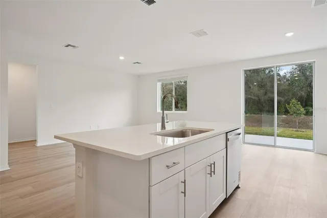 a kitchen with white cabinets a sink and a large window
