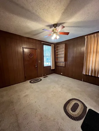 en empty room with windows and chandelier fan