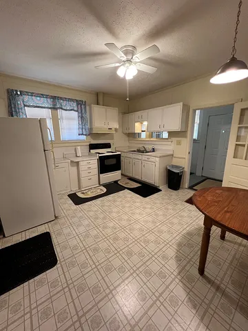 a large kitchen with a stove a refrigerator a sink dishwasher a dining table and chairs with wooden floor