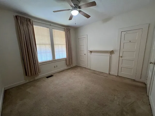 an empty room with windows and fan