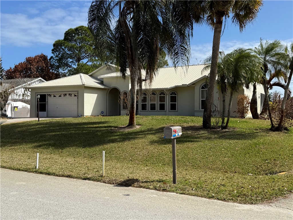 a view of a white house with a yard and palm trees