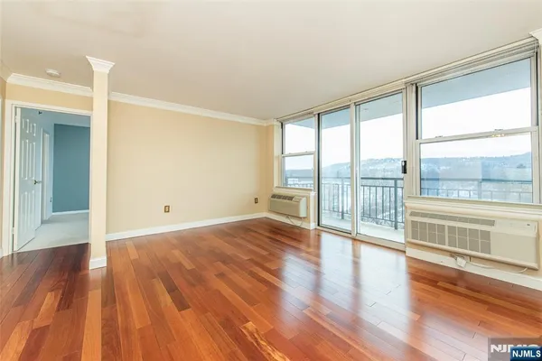 a view of empty room with wooden floor and fan