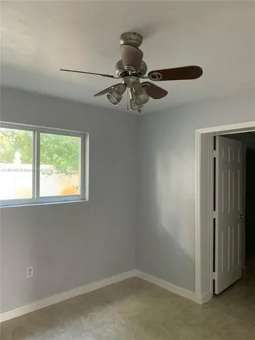 an empty room with a window and a fan