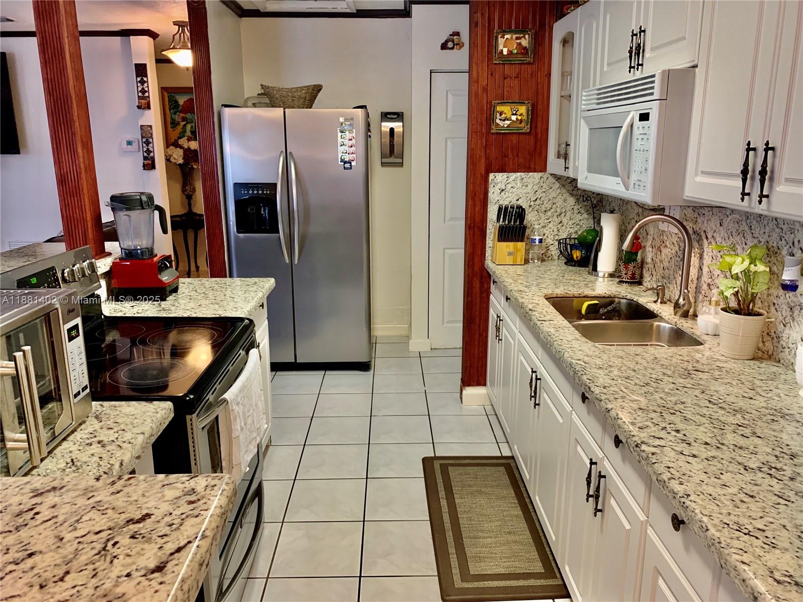 6180 Southwest 42nd Court Davie, FL 33314 - Photo 7 of 25 a kitchen with granite countertop a stove a sink and a refrigerator