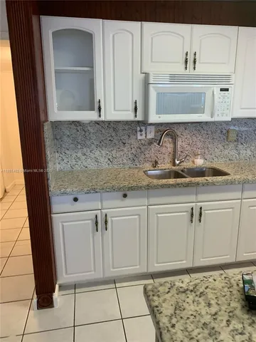 a white kitchen with granite countertop white cabinets and a sink