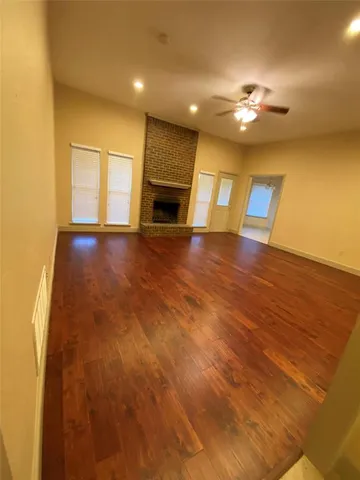 a view of an empty room with window and wooden floor